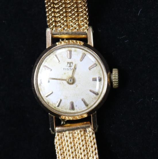 A ladys gold plated and steel Tissot manual wind wrist watch on a textured gold bracelet.